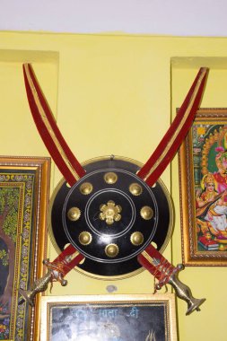 Duvarda iki kılıçla asılı bir kılıçla, karşı karşıya, Hindu askeri sınıfının sembolü, Kshatriya 'nın indiğini iddia ediyor..