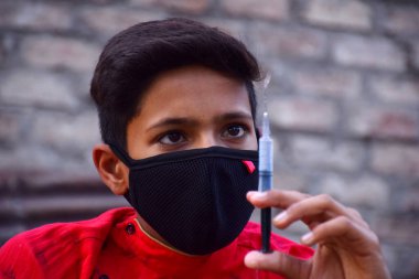 13 yaşındaki Asyalı sevimli çocuk koruyucu maske takıyor, şırıngalı, Corona virüsünü önlüyor (Covid -19) ve kirliliği önlüyor.