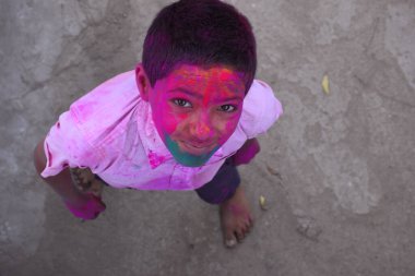 Çocuk renklerle oynuyor, neşeli bir ruh hali içinde. Hint festivali için kavram Holi