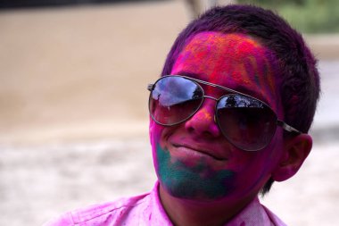 Renklerle oynayan, okul üniformalı gözlüklü, Hint festivali için konsept Holi