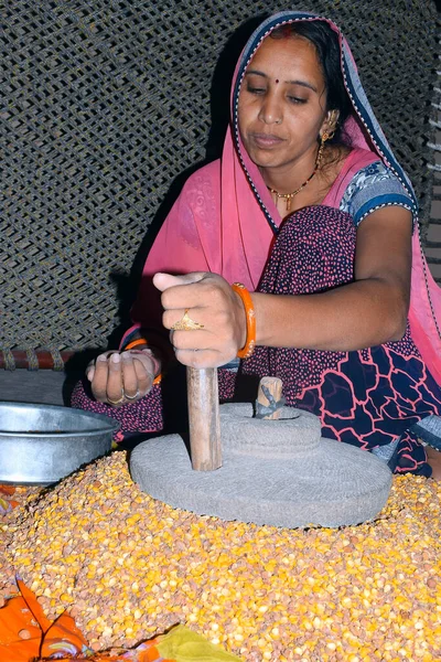 A village woman grinds gram in an old hand operated flour mill