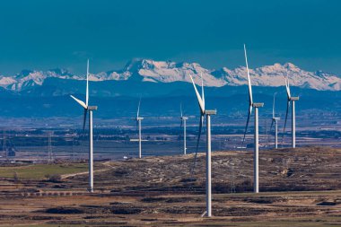 Arka planda Pireneler Dağları olan rüzgar türbinleri