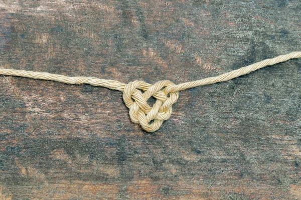 sisal rope bonding on wooden Background, in heart shape knot on metal background. Love symbol. Love, Valentine\'s Day Concept. Flat lay