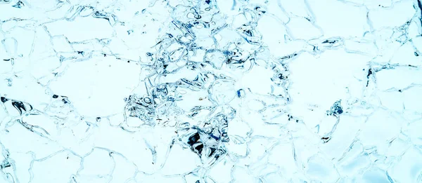 Transparent Ice Floe with cracked crystals blue texture background against light. Cold winter ice texture. close up, macro abstract pattern detail