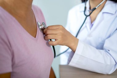 Doktor steteskopla hastayı muayene eder ve sonuçları kaydeder..