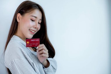 Kırmızı kredi kartı tutan, uzun saçlı, güzel bir Asyalı kadının portresi. Gözleri karta bakıyor. İndirimli ürünlere göre alışverişe hazır..