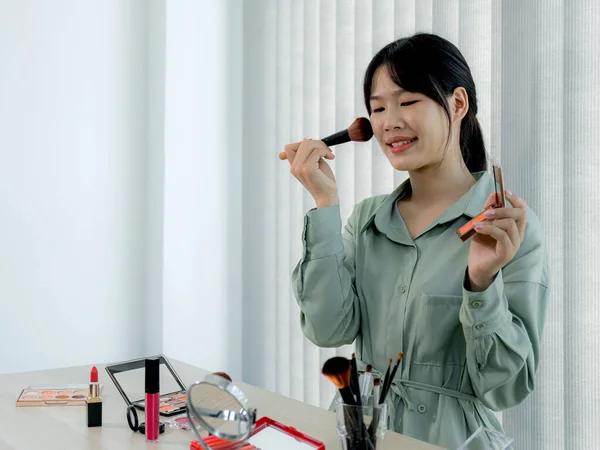 Beautiful Asia female vlogger is showing cosmetics makeup products while recording video and giving recommended for her beauty blog with digital smartphone.