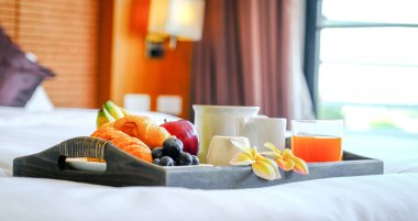 Lüks otel odasındaki yatakta bir tepside kahvaltı. Turist seyahatine hazır..