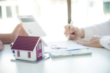 Ev modeli. Emlak acentesinin iş sözleşmesini, kirayı, satın almayı, ipoteği, krediyi veya ev sigortasını alıcıya açıklamasının ardından el imzası..