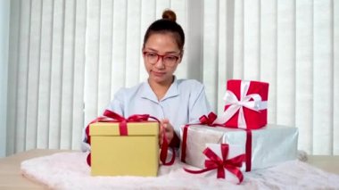 Mavi gömlekli bir kadın, Noel, Yeni Yıl, Sevgililer Günü gibi özel bayramlar için kırmızı kurdeleli bir hediye kutusu açıyor..