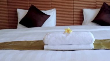 Plumeria ve havlular otel hizmetçisinin önünde lüks otel odasındaki yatağı turist yolculuğuna hazır hale getiriyor..