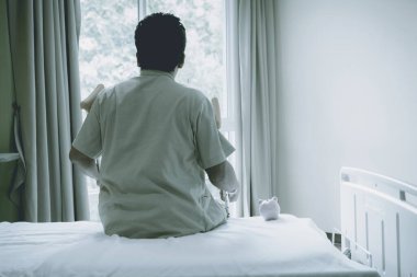 Hastanın erkek bacağının arkası ameliyat sonrası yürümek için koltuk değneği kullanıyor. Kırık kemikler ve pembe domuz kumbarası..