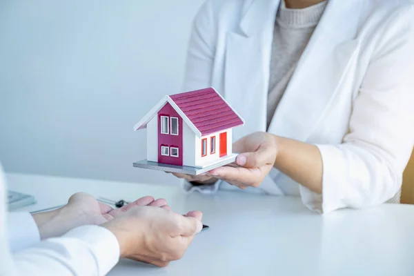 Home Model in hands, The real estate agent explains the business contract, rent, purchase, mortgage, a loan, or home insurance to the business buyer.
