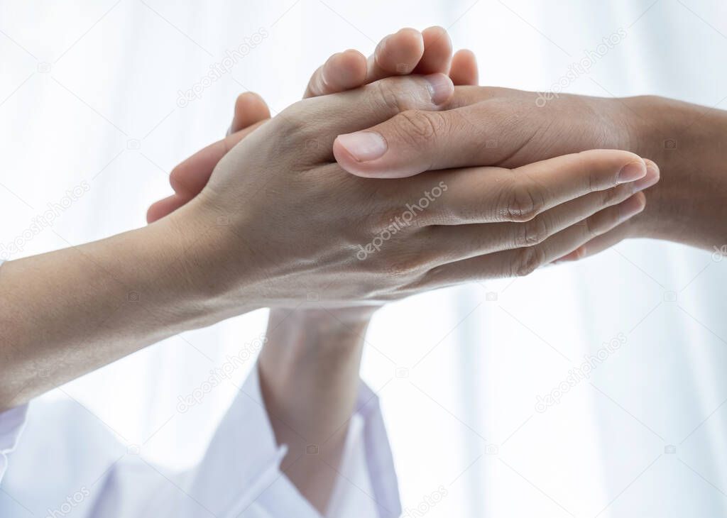 The doctor hands holding patient hand to encouragement and explained the health examination results.