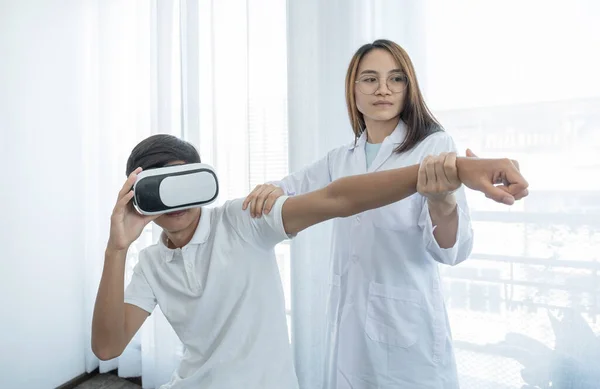 Fizik tedavi uygulayan kadın doktor, VR kutusu olan bir erkek hastanın elini uzatarak, teknoloji kavramı, onu tedavi etmek için eve gelen bir doktorun hissine yardımcı oldu..