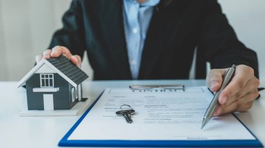 ev modeli. Emlakçının elinde kalem tutması ve iş sözleşmesini, kirayı, satın almayı, ipoteği, krediyi ya da ev sigortasını açıklaması.