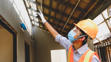 Müteahhit güvenlik endüstrisi projesinde çalışıyor, bina planlarını kontrol ediyor ve inşaat alanlarının büyüklüğünü ve kalitesini araştırıyor..