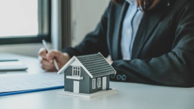 ev modeli. Emlakçı, iş sözleşmesini, kirayı, satın almayı, ipoteği, krediyi ya da ev sigortasını alıcıya açıkladıktan sonra el imzası..