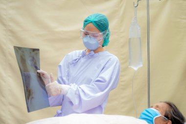 Doktor, akciğer röntgeninin sonuçlarını hastane odasında yatan yaşlı bir hastaya açıklıyor..