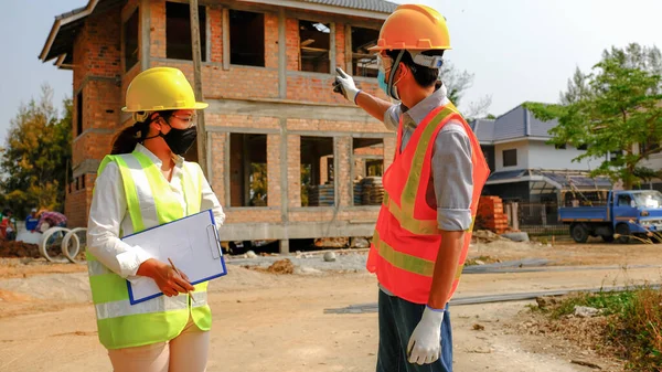 Mühendis müteahhit ekibi iş güvenliği planlama projesiyle buluşuyor ve inşaat sahasında tasarımı kontrol ediyor..