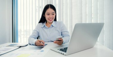 İş kadını grafiği analiz ediyor ve iş hedeflerini belirlemek ve yeni hedefe ulaşmayı planlamak için merkez ofiste bilgisayarla video konferans düzenliyor..