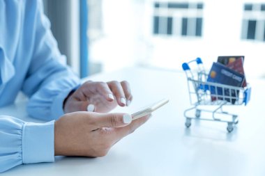 Tüketici kadın akıllı telefon ve sahte kredi kartı kullanıyor. Ev ofisinden gelen indirimli ürünlere göre online finans alışverişini ödemeye hazır..