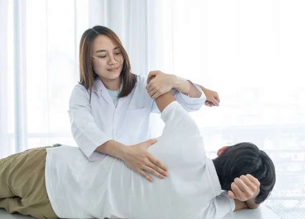 Doctora Haciendo Fisioterapia Extendiendo Espalda Paciente Masculino — Foto de Stock