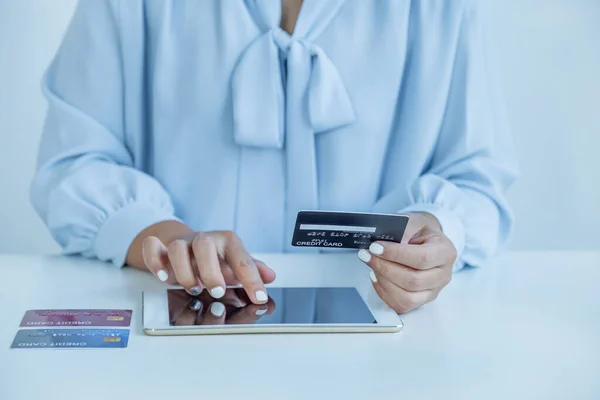 Consumer woman hand holding a mock up credit card, ready to spending pay online finance shopping according to discount products via Tablet from home office.