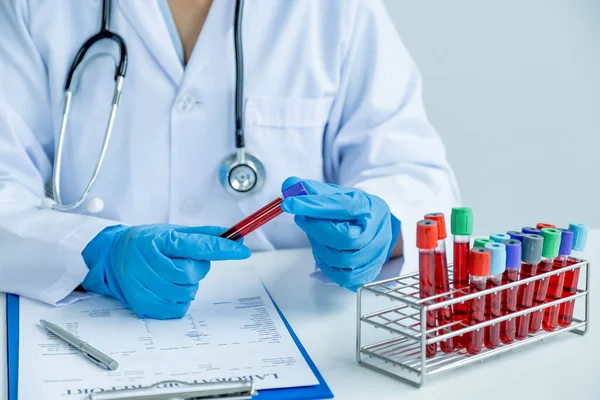 Kan tüpünü tutan doktor muayene sonuçlarını ve hastanın ilaç kullanımını dosyaya kaydediyor. Tıbbi kontrol kavramı..