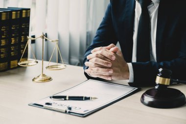 El, Avukat oturuyor ve ofiste hukuki danışmanlık hizmeti veriyor adalet terazisi ve tokmak çekiciyle.