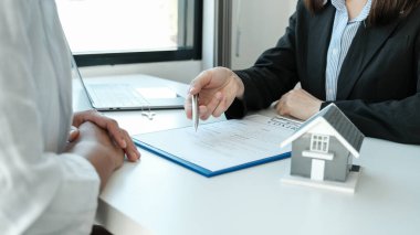 Emlakçının elinde kalem tutması ve iş sözleşmesini, kirayı, satın almayı, ipoteği, krediyi veya ev sigortasını müşteri kadına açıklar..