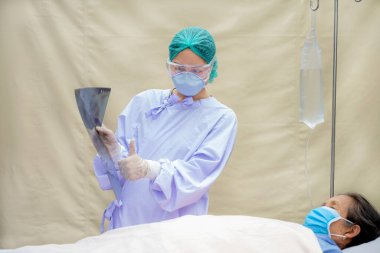 Doktor, akciğer röntgeninin sonuçlarını hastane odasında yatan yaşlı bir hastaya açıklıyor..