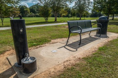 Sonbaharda güneşli bir sonbaharda, arka planda ağaçlık alanların olduğu bir yerde halka açık bir çeşmede oturmalı ve yol boyunca bir çöp tenekesi olmalı.