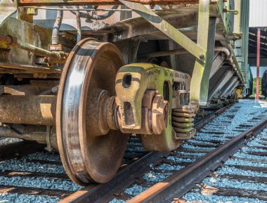 Demiryolu tekerleğinin ön görüntüsü. Yıpranmış ve paslanmış bir yük vagonunda tren raylarında duruyor. Bazı malları taşımaya hazır.