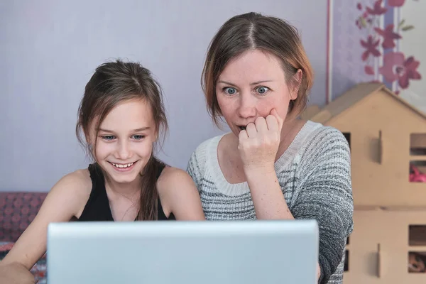 Maman et sa fille regardent un ordinateur portable ensemble et leur fille rit et leur mère est surprise — Photo