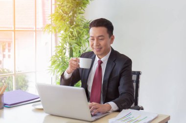 Masasında kahvesini yudumlayan Asyalı bir adamın müdürü..