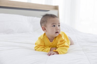 Temiz beyaz bir yatakta uzanmış Asyalı bir bebek..