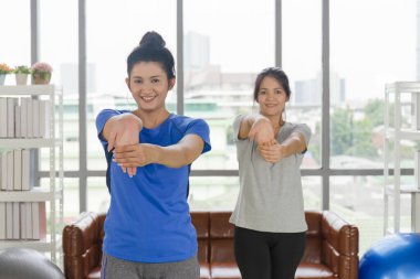 İki orta yaşlı Asyalı kadın evlerinde yoga yapıyor..