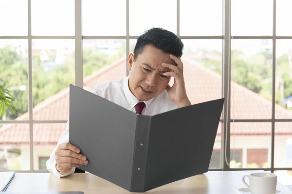 アジアの男性マネージャーは会社の会計をチェックし 彼のオフィスで頭痛で深刻だった — ストック写真