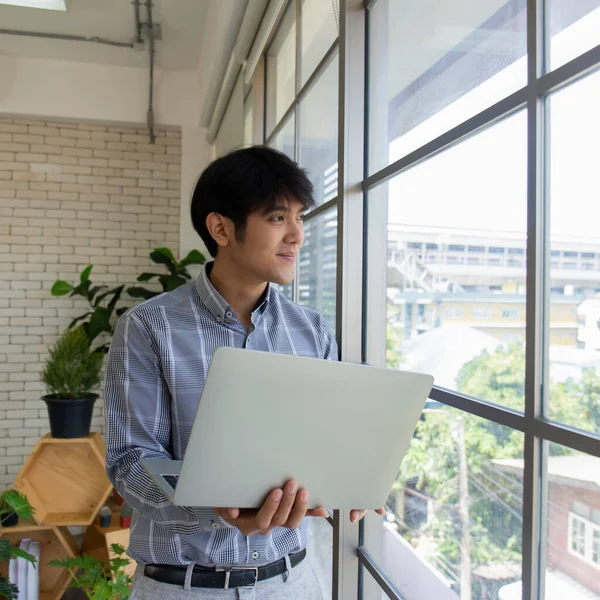 Молодой Азиатский Бизнесмен Ноутбуком Стоящим Стеклянного Окна — стоковое фото
