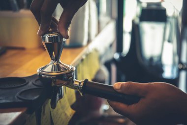 Barista, taze kavrulmuş kahvenin akış makinesinden sulanması ihtimaline karşı kahve tozunu bloğa bastırmak için elini kullanıyor..