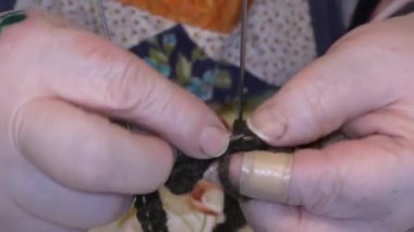 Yaşlı bir kadın yün örgü iğneleriyle örüyor.