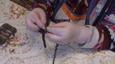 Yaşlı bir kadın yün örgü iğneleriyle örüyor.