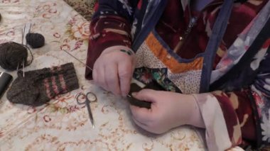 Yaşlı bir kadın yün örgü iğneleriyle örüyor.