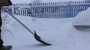 Sokaktaki insanlar karları kürekle temizliyorlar.