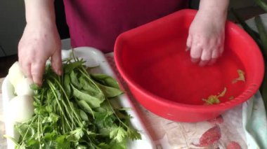 Kadın taze otları suyla yıkıyor. 