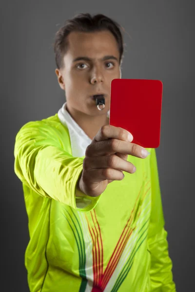 Soccer referee in yellow shirt showing the red card