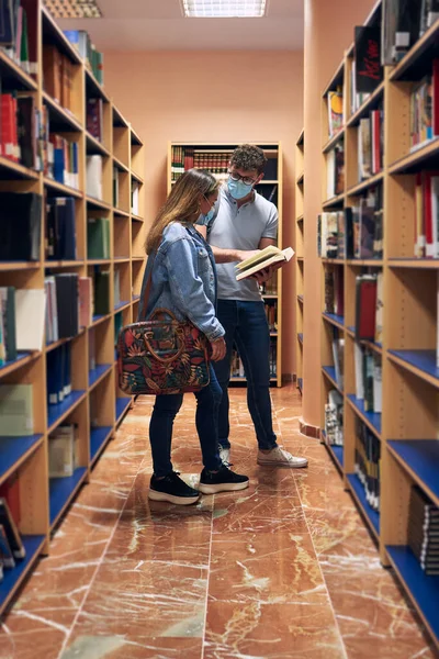 Dois Jovens Usando Máscaras Estão Olhando Para Livro Biblioteca — Fotografia de Stock