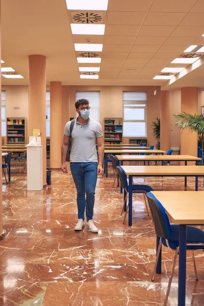 Boy with mask and backpack enters an empty library