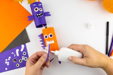 Cadılar Bayramı süsü. DIY ve çocukların yaratıcılık konsepti. Adım adım: Turuncu ve mor kağıtlardan oluşan tuvalet kağıdından canavar yap. 14. adım Kolları, kanatları yapıştırın